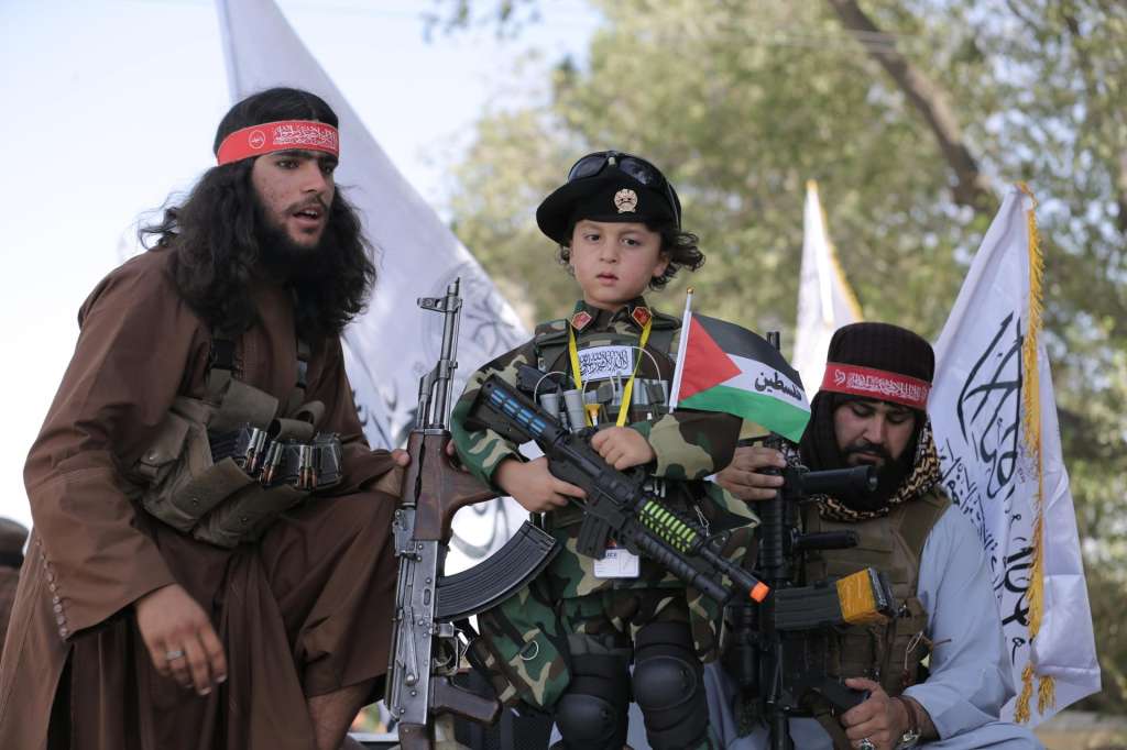Kabul (Afghanistan), 15/08/2026.- A child stands with Taliban government security officials as they secure a rally during celebrations to mark the fifth anniversary of the Taliban takeover of Afghanistan, in Kabul, Afghanistan, 15 August 2026. Afghanistan marks five years since the Taliban returned to power and entered Kabul on 15 August 2021, following the collapse of the former government and withdrawal of US-led forces. (Afganistán) EFE/EPA/SAMIULLAH POPAL