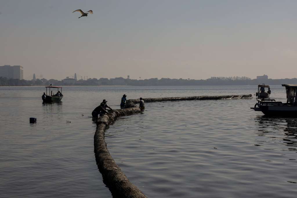 BRA01. RIO DE JANEIRO (BRASIL), 07/06/2023.- Fotografía que muestra hombres mientras trabajan en una barrera de contención de 200 metros de extensión hoy, en una playa de la bahía de Guanabara en Río de Janeiro (Brasil). Un proyecto lanzado este miércoles en Río de Janeiro, en la víspera del Día Mundial de los Océanos, busca una solución sostenible para recoger basura flotante en áreas costeras. EFE/Antonio Lacerda