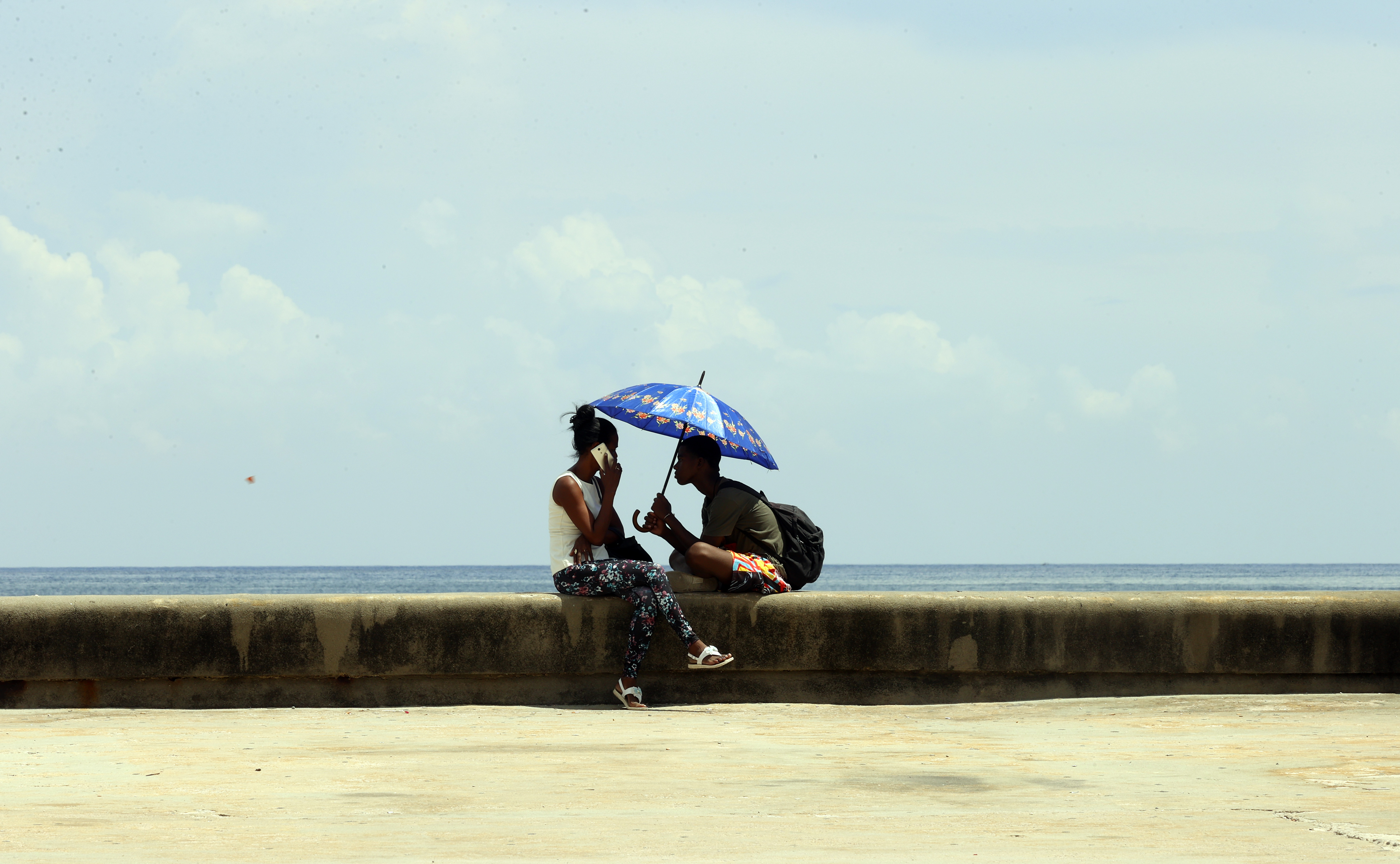-FOTODELDÍA- AME4347. LA HABANA (CUBA), 20/07/2023.- Una pareja se protege del sol mientras conversa en una zona del Malecón hoy, en La Habana (Cuba). EFE/ Ernesto Mastrascusa