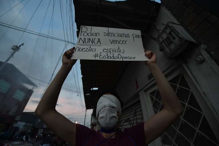 Un hombre encapuchado sostiene un cartel