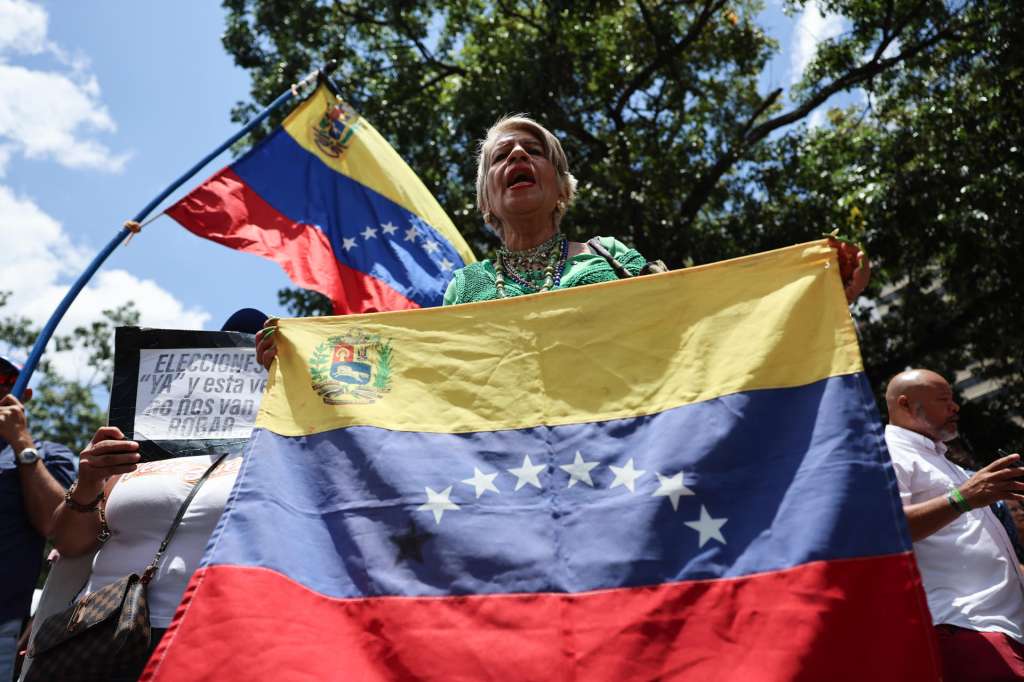 AME8406. CARACAS (VENEZUELA), 12/08/2026.- Una persona sostiene una bandera durante una manifestación este miércoles, mientras la primera ronda de negociación entre el Gobierno y la oposición de Venezuela, promovida por Estados Unidos, ocurre al interior del hotel Meliá Caracas, en Caracas (Venezuela). EFE/ Miguel Gutiérrez
