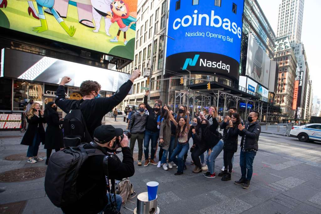 Los empleados de Coinbase se reúnen para una foto grupal durante la oferta pública inicial (OPI) de la compañía fuera del Nasdaq MarketSite en Nueva York, Estados Unidos.