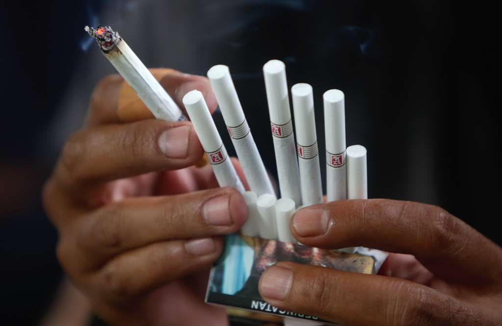 Yakarta (Indonesia), 27/12/2022.- Un hombre fuma un cigarrillo en una calle de Yakarta, Indonesia, este martes. El presidente de Indonesia, Joko Widodo, ha emitido un Decreto Presidencial de la República de Indonesia sobre el 202 programa de redacción de reglamentos del gobierno, uno de ellos es estipular la prohibición de la venta de cigarrillos en barra, sobre la restricción de sustancias adictivas en los productos del tabaco para la salud. EFE/ADI WEDA