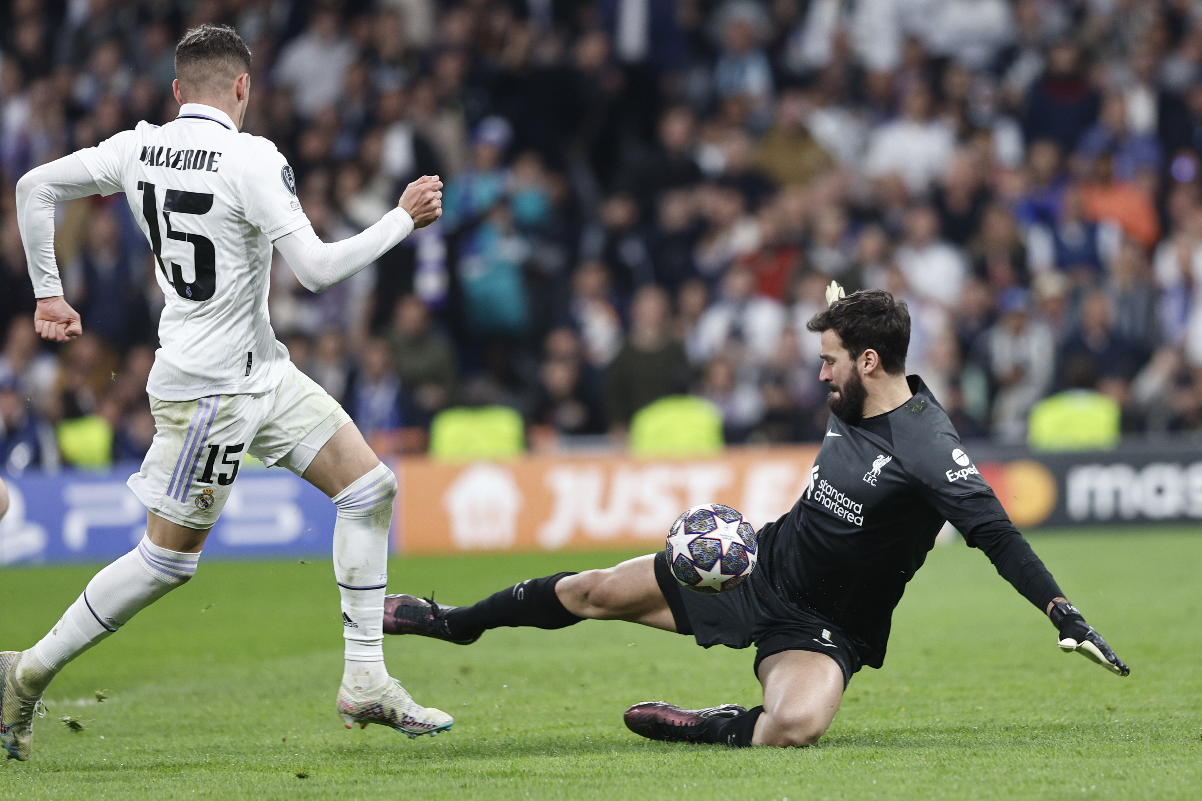 MADRID, 15/03/2023.- El centrocampista del Real Madrid Fede Valverde (i) trata de superar al portero Alisson Becker, del Liverpool, durante el partido de vuelta de los octavos de final de la Liga de Campeones que Real Madrid y Liverpool disputan este miércoles en el estadio Santiago Bernabéu, en Madrid. EFE/Rodrigo Jiménez