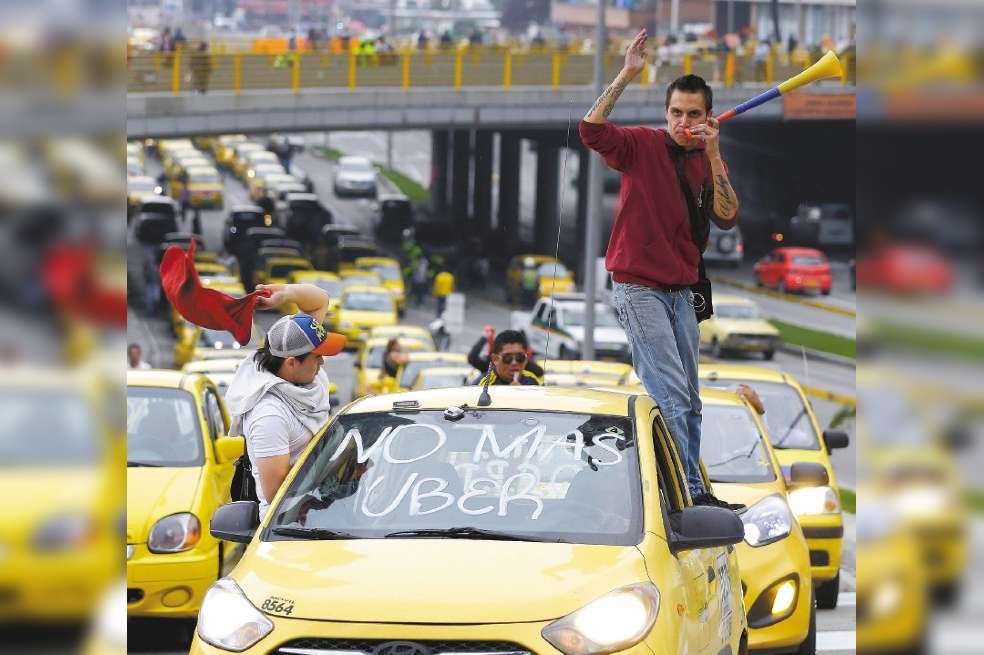 FILE - In this March 14, 2016 file photo, a cab driver with "No more Uber" written on his windshield joins a protest against the app-based taxi service as they block a road in downtown Bogota, Colombia. Colombias antitrust regulator fined the ride-sharing app Uber $625,000 on Monday, Aug. 12, 209 for allegedly obstructing an investigation into its operations in the country. (AP Photo/Fernando Vergara, File)