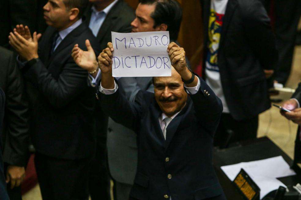 El diputado opositor Luis Silva sostiene un cartel contra el presidente venezolano en el que se lee “Maduro dictador”. / EFE