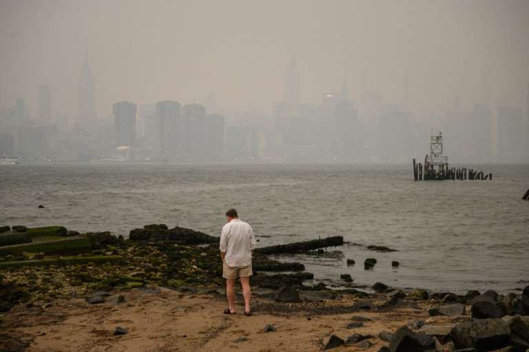Un hombre ante el horizonte de la ciudad de Nueva York y el East River envueltos en humo, en Brooklyn, el 5 de junio de 2023.
