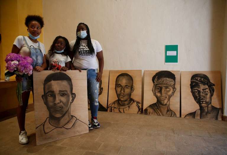Familiares de Juan Manuel Montaño, joven asesinado en la masacre de Llano Verde, fueron registrados este viernes al sostener un retrato del menor masacrado, durante un acto simbólico en homenaje a las víctimas, en Cali