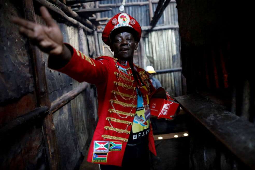 Stanley Ngara le pide a su asistente más condones mientras entra a un bar para distribuirlos en los barrios bajos de Kibera, Nairobi, en Kenia. / EFE