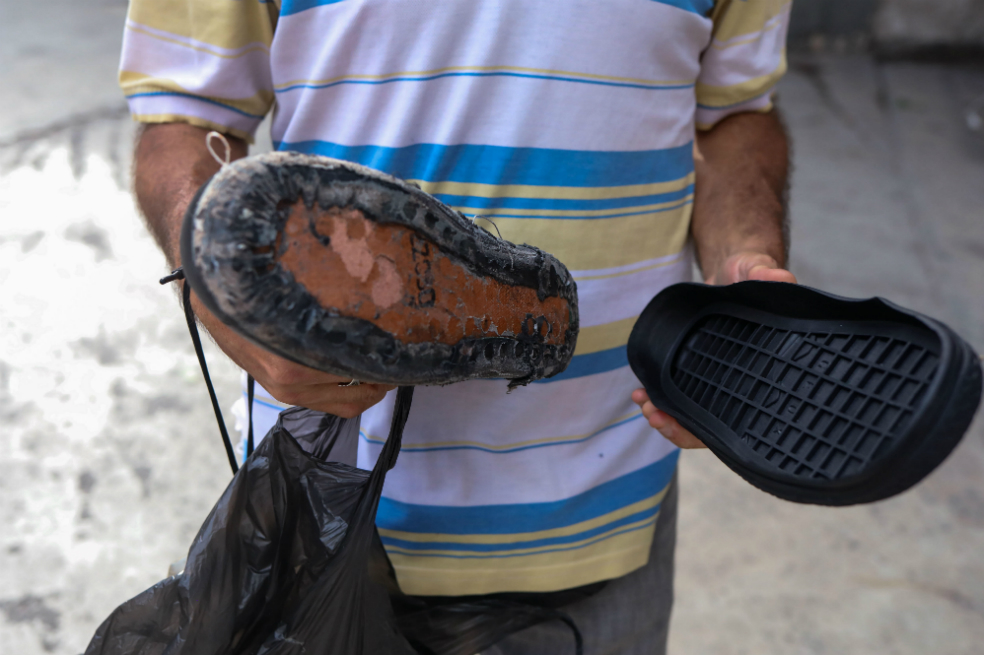 Un hombre que muestras las suelas de repuesto para un par de zapatos, en Caracas, Venezuela. Miles de venezolanos caminan por las calles de la ciudad con los zapatos rotos o desgastados. / EFE