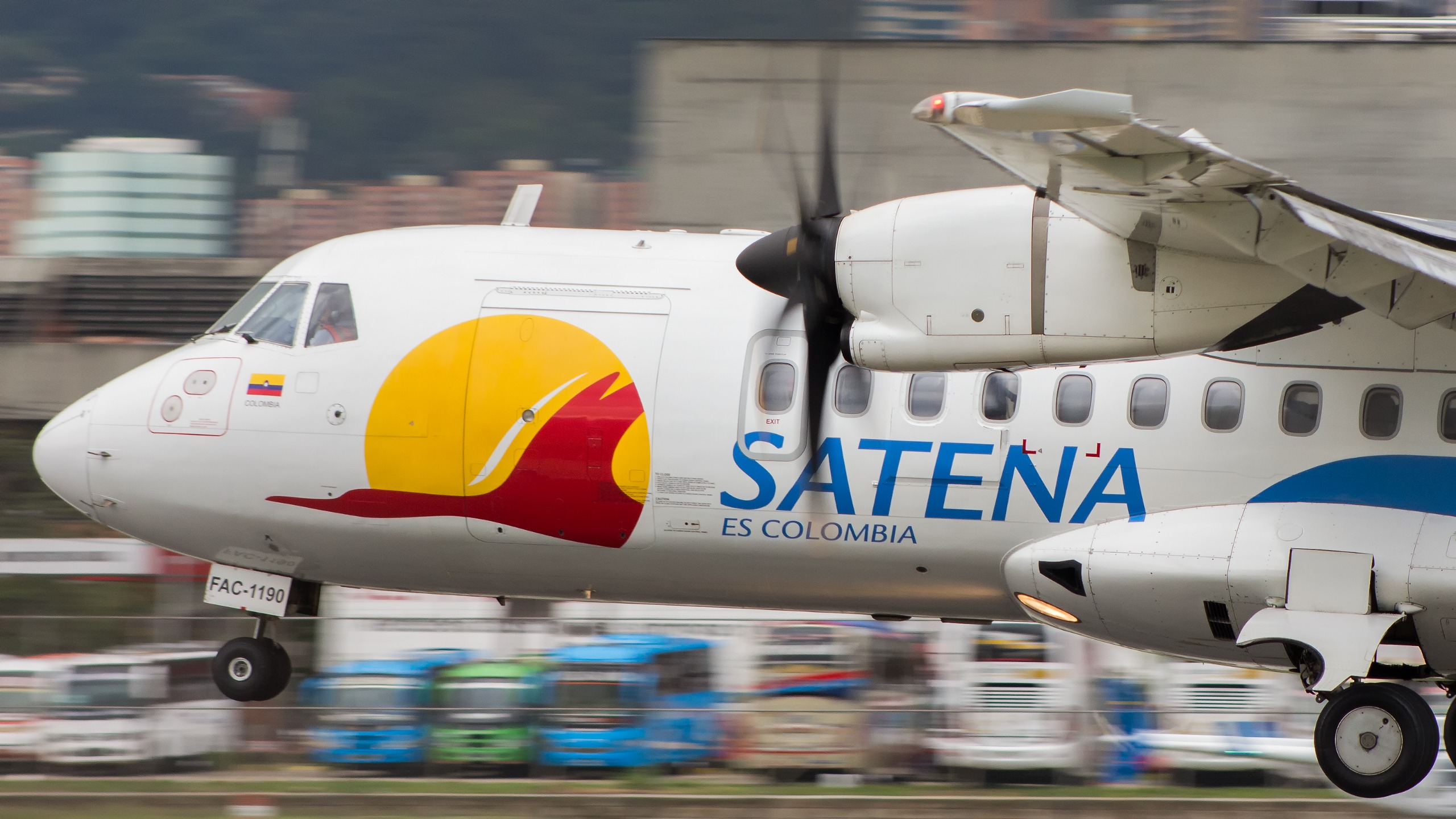 Avión de Satena en movimiento, con logo amarillo y rojo en el fuselaje y la frase "Satena es Colombia".