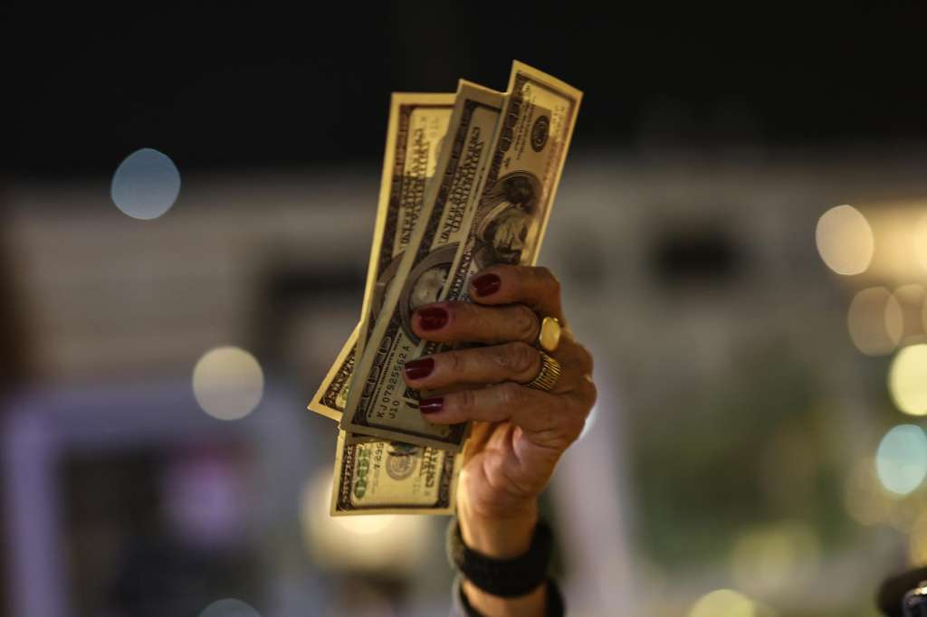 Tel Aviv (Israel), 20/12/2025.- A demonstrator holds up US dollar bills during in a protest against Israeli Prime Minister Benjamin Netanyahu's government at Habima theater square in Tel Aviv, Israel, 20 December 2025. (Protestas) EFE/EPA/ATEF SAFADI