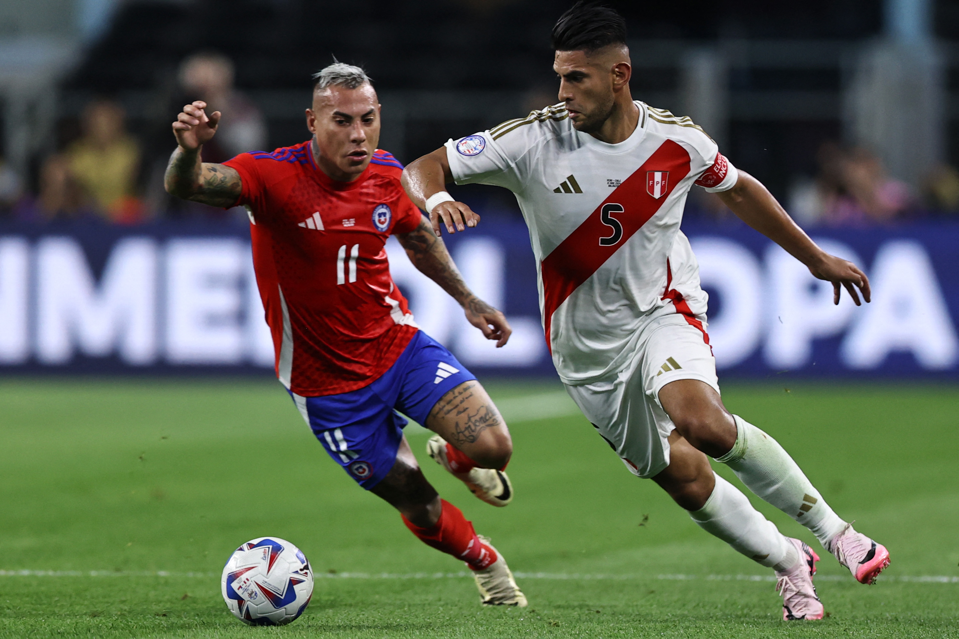 Carlos Zambrano de Perú (der.) y Eduardo Vargas de Chile luchan por el balón durante el partido del Grupo A de la Copa América 2024.