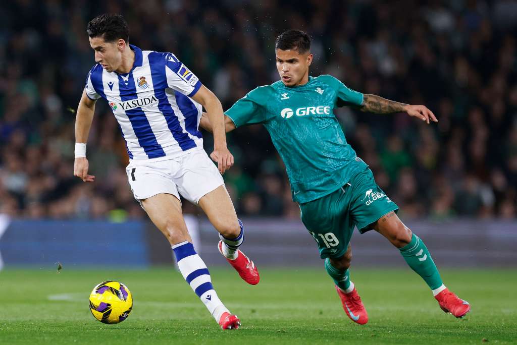 SEVILLA, 16/02/2025.- El defensa marroquí de la Real Sociedad Naif Aguerd (i) se escapa del colombiano Cucho Hernández, del Betis, durante el partido de la jornada 24 de LaLiga que Real Betis y Real Sociedad disputan hoy domingo en el estadio Benito Villamarín. EFE/ Julio Munoz