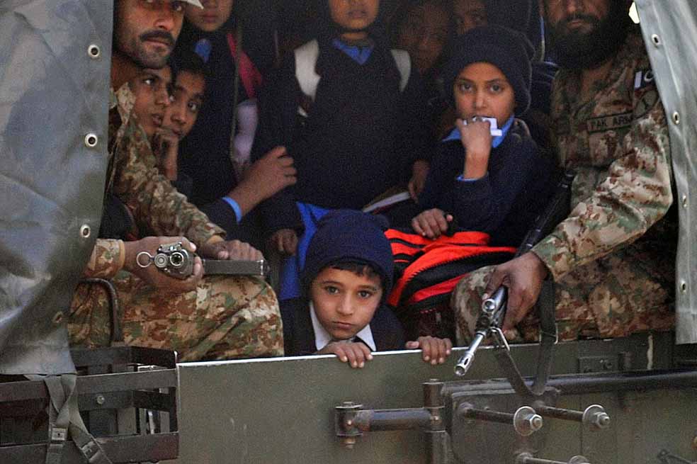 Soldados paquistaníes transportan a niños rescatados de la escuela atacada en Peshawar. / AFP