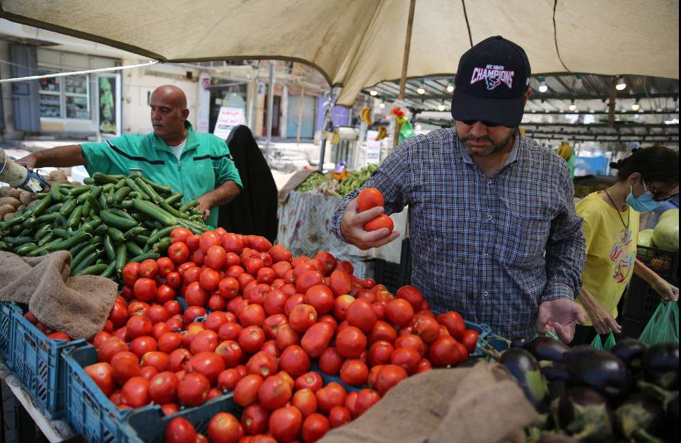 Iraqis, some wearing a protective mask amid the COVID-19 pandemic, buy fresh produce from a street seller at a market in Karrada, in the capital Baghdad, on July 14, 2020. Iraq, in a bid to prevent the spread of the deadly COVID-19 illness, shut its 32 border crossings to goods and people coming from Iran, Turkey, Syria, Jordan and Saudi Arabia in mid-March, which helped its agriculture ministry accelerate a campaign to make Iraqi food markets self-sustainable, after years of relying on foreign imports for half of their supply. / AFP / AHMAD AL-RUBAYE