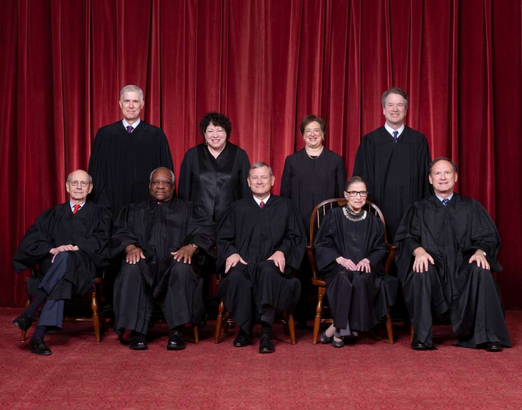 Primera fila, de izquierda a derecha: juez asociado Stephen G. Breyer, juez asociado Clarence Thomas, juez presidente John G. Roberts, Jr., juez asociado Ruth Bader Ginsburg, juez asociado Samuel A. Alito. Fila de atrás: juez asociado Neil M. Gorsuch, juez asociado Sonia Sotomayor, juez asociado Elena Kagan, juez asociado Brett M. Kavanaugh.