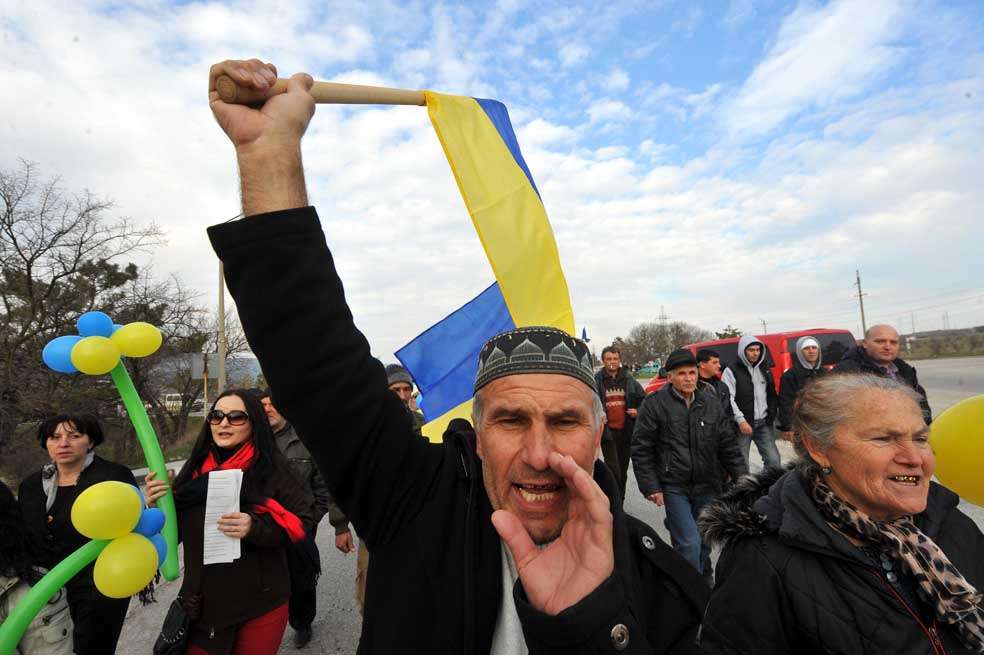 Un tártaro enarbola la bandera de Ucrania en una protesta contra la posible anexión a Rusia. / AFP
