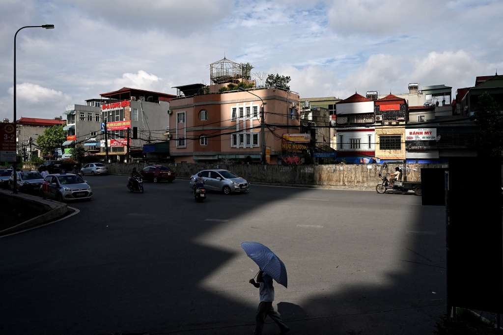 En esta foto de archivo tomada el 16 de junio de 2020, un hombre lleva un paraguas para protegerse del sol en una calle de Hanoi. - Vietnam registró una temperatura máxima récord de 44,1 grados centígrados el 6 de mayo de 2023, según las autoridades. (Foto por: Manan VATSYAYANA / AFP)