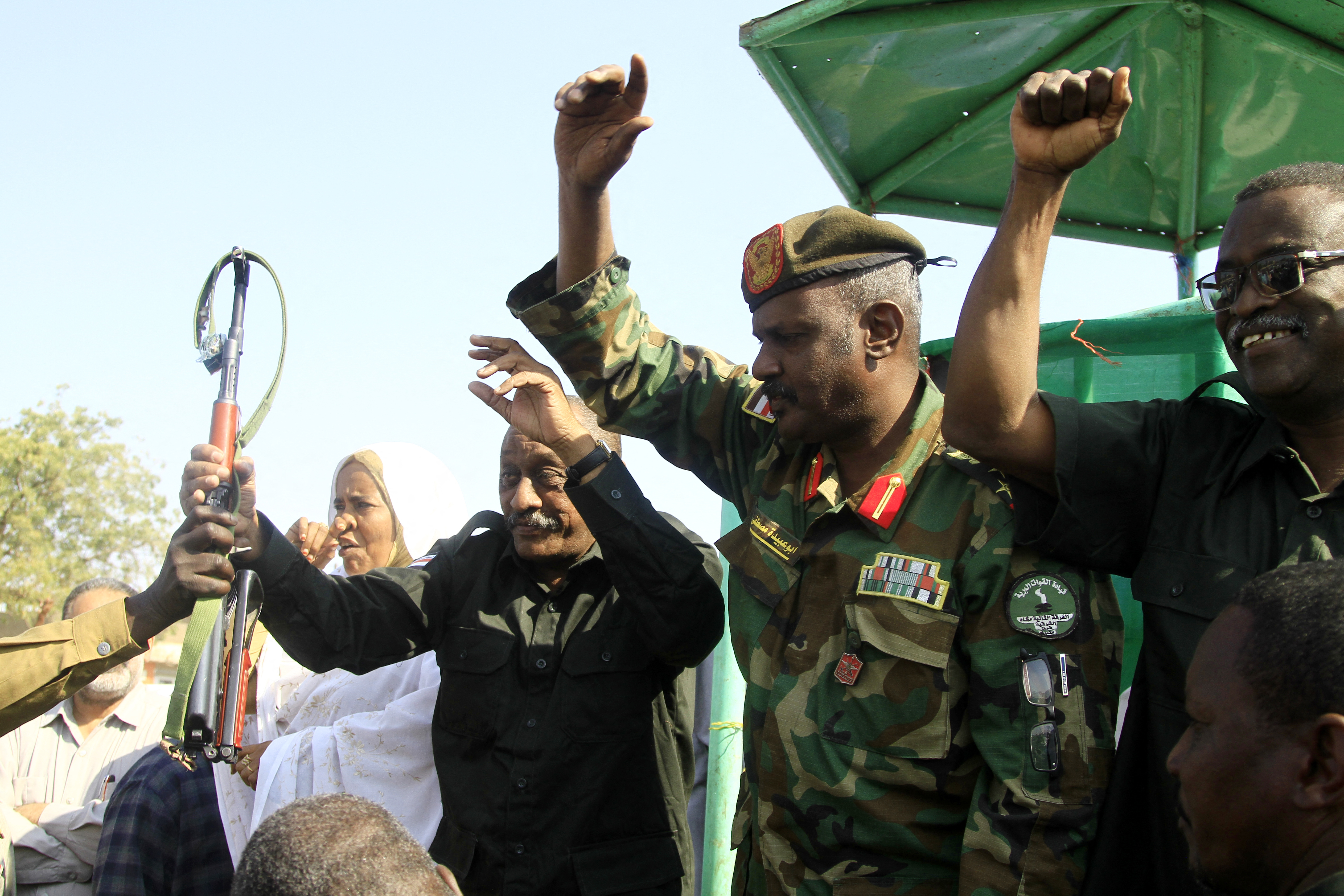 Oficiales del ejército sudanés saludan a la multitud durante una reunión con los partidarios del gobernador de la ciudad y miembros de la resistencia popular armada sudanesa, que apoya al ejército, en Gedaref, Sudán.