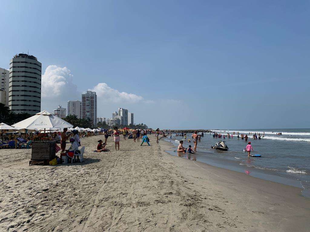 Se observa a turistas y locales tomando el sol y sumergiéndose en el mar.