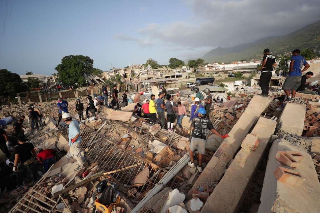 AME5030. LA GUAIRA (VENEZUELA), 26/06/2026.- Personas realizan labores de búsqueda en una zona afectada por un terremoto, este viernes en La Guaira (Venezuela). Venezuela afrontó su tercer día de emergencia con apoyo de brigadas de rescate de nueve países, entre ellos Estados Unidos y España, que se han sumado a las labores de búsqueda de supervivientes o fallecidos, tras el doble terremoto del pasado miércoles que deja al menos 920 muertos y 3.360 heridos, según cifras oficiales. EFE/ Ronald Peña R