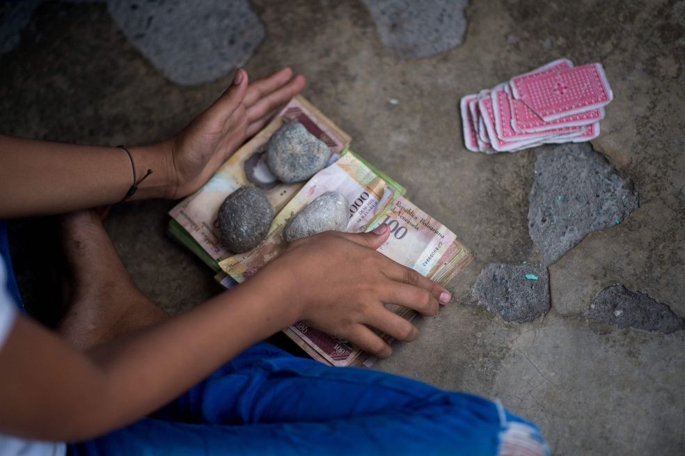 Los niños juegan a las cartas y apuestan con billetes de bolívares venezolanos no utilizados en una calle del pueblo de Puerto Concha, estado Zulia, Venezuela.