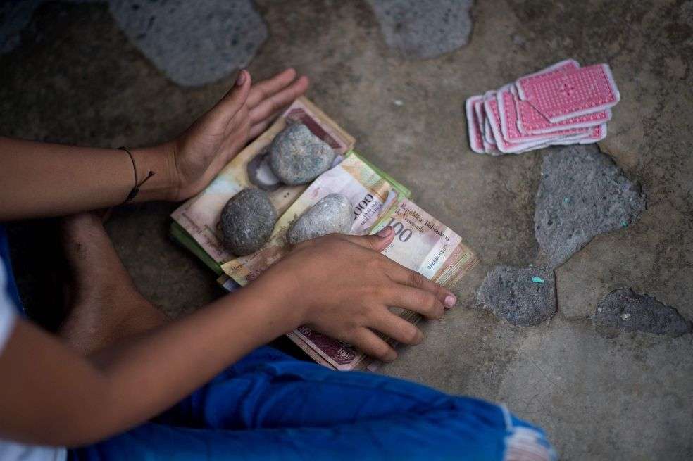 Los niños juegan a las cartas y apuestan con billetes de bolívares venezolanos no utilizados en una calle del pueblo de Puerto Concha, estado Zulia, Venezuela.