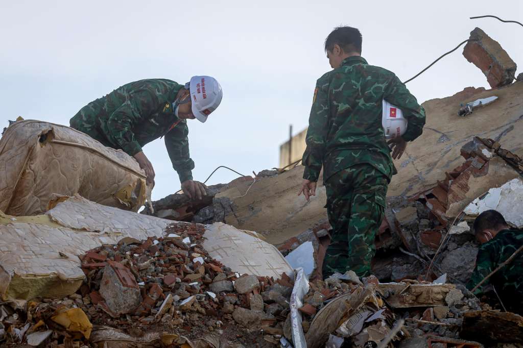 AME6165. LA GUAIRA (VENEZUELA), 30/06/2026.- Rescatistas de Vietnam caminan este martes sobre escombros de edificaciones destruidas en Catia La Mar, La Guaira (Venezuela). La cifra de fallecidos por el doble terremoto ocurrido el pasado miércoles en la zona norte de Venezuela ascendió a 1.943 y la de heridos a 10.571, informó el presidente del Parlamento, Jorge Rodríguez. EFE/ Miguel Gutiérrez