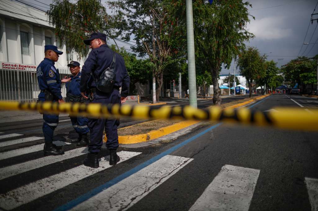 AME5106. SAN SALVADOR (EL SALVADOR), 03/02/2024.- Agentes de la policía custodian la avenida olímpica hoy durante los preparativos electorales en San Salvador (El Salvador). La inesperada lluvia con la que amaneció San Salvador complicó este sábado el reparto de las papeletas hacia los colegios electorales, destinadas a unos comicios el domingo en los que se espera que el presidente salvadoreño, Nayib Bukele, alcance una rotunda mayoría, algo que parece asimilar la oposición, que no se dejó ver en unos puntos de votación monopolizados por el azul y blanco del partido oficial Nuevas Ideas (NI). EFE/Bienvenido Velasco