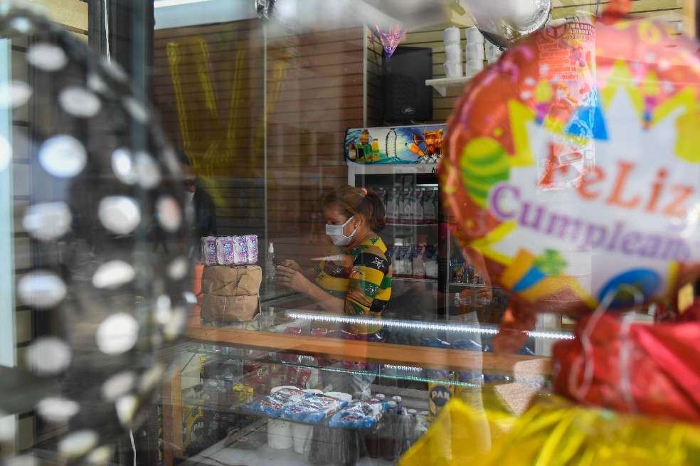 A woman buys groceries at a pinatas and costumes store now selling food and cleaning products, due to the COVID-19 coronavirus pandemic, at Sabana Grande Boulevard in Caracas on July 15, 2020, The COVID-19 pandemic, which reached Venezuela in mid-March and has infected some 10,000 people, according to official figures, forced the closure of 90% of the businesses in the Caribbean country, according to the private company Consecomercio. Only supermarkets, pharmacies and other businesses considered "essential" by the socialist government are exempted from the national quarantine, which has been tightened in Caracas due to the spread of the virus. / AFP / Federico PARRA