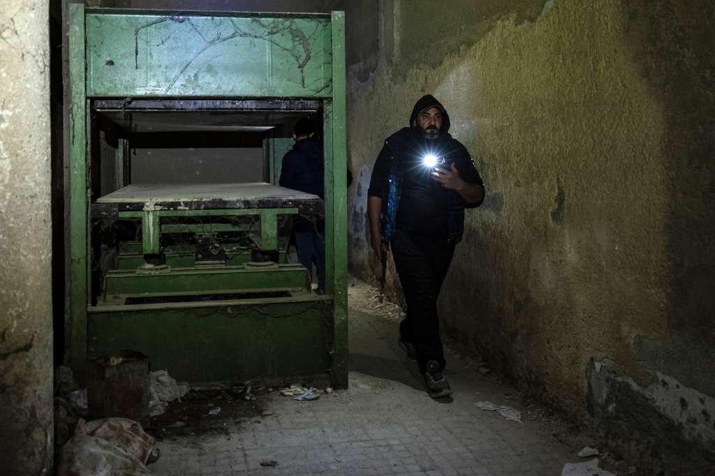 Un hombre armado pasa junto a una prensa mecánica en la prisión de Saydnaya, en Damasco, el 11 de diciembre de 2024.