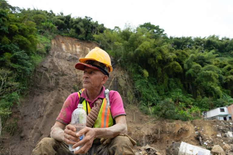 Un hombre sentado con una botella de agua en su manos mira a su derecha