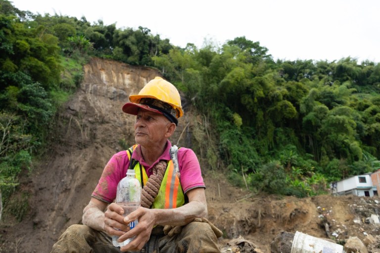 Un hombre sentado con una botella de agua en su manos mira a su derecha