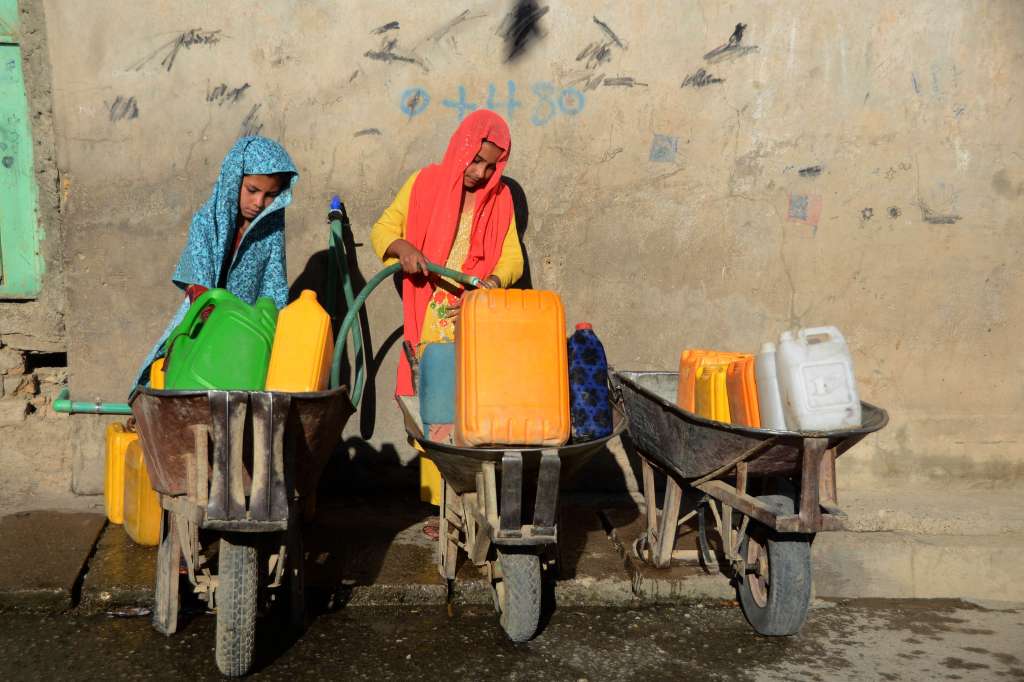 (FILES) Girls fill containers with drinking water from a tap in Kandahar on May 24, 2022.