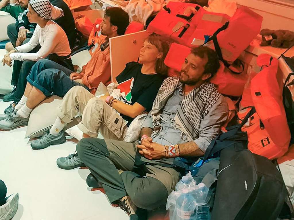 This handout picture released by the Israeli Foreign Ministry shows Swedish climate activist Greta Thunberg (C) and Brazilian activist Thiago Avila (R), along with other activists, after the Israeli navy intercepted the Global Sumud Flotilla carrying humanitarian aid to Gaza on October 1, 2025, as stated by the ministry.