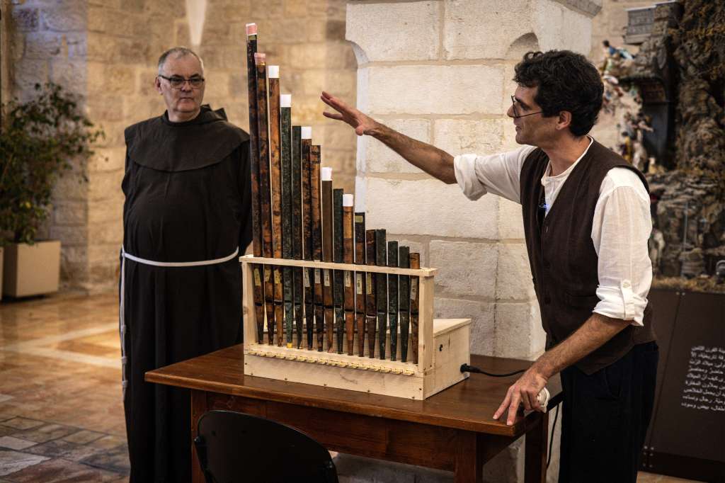 Medieval musicologist David Catalunya (L) gives a briefing about the history of a functioning replica containing original pipes from the oldest organ in Christendom, during the instrument's unveiling and playing at the Saint Saviour�s Monastery in the old city of Jerusalem on September 9, 2025. The pipes of a medieval organ, buried for centuries and discovered near the Church of the Nativity in Bethlehem in the occupied West Bank, are once more filling a Jerusalem monastery with ancient melodies. (Photo by JOHN WESSELS / AFP)