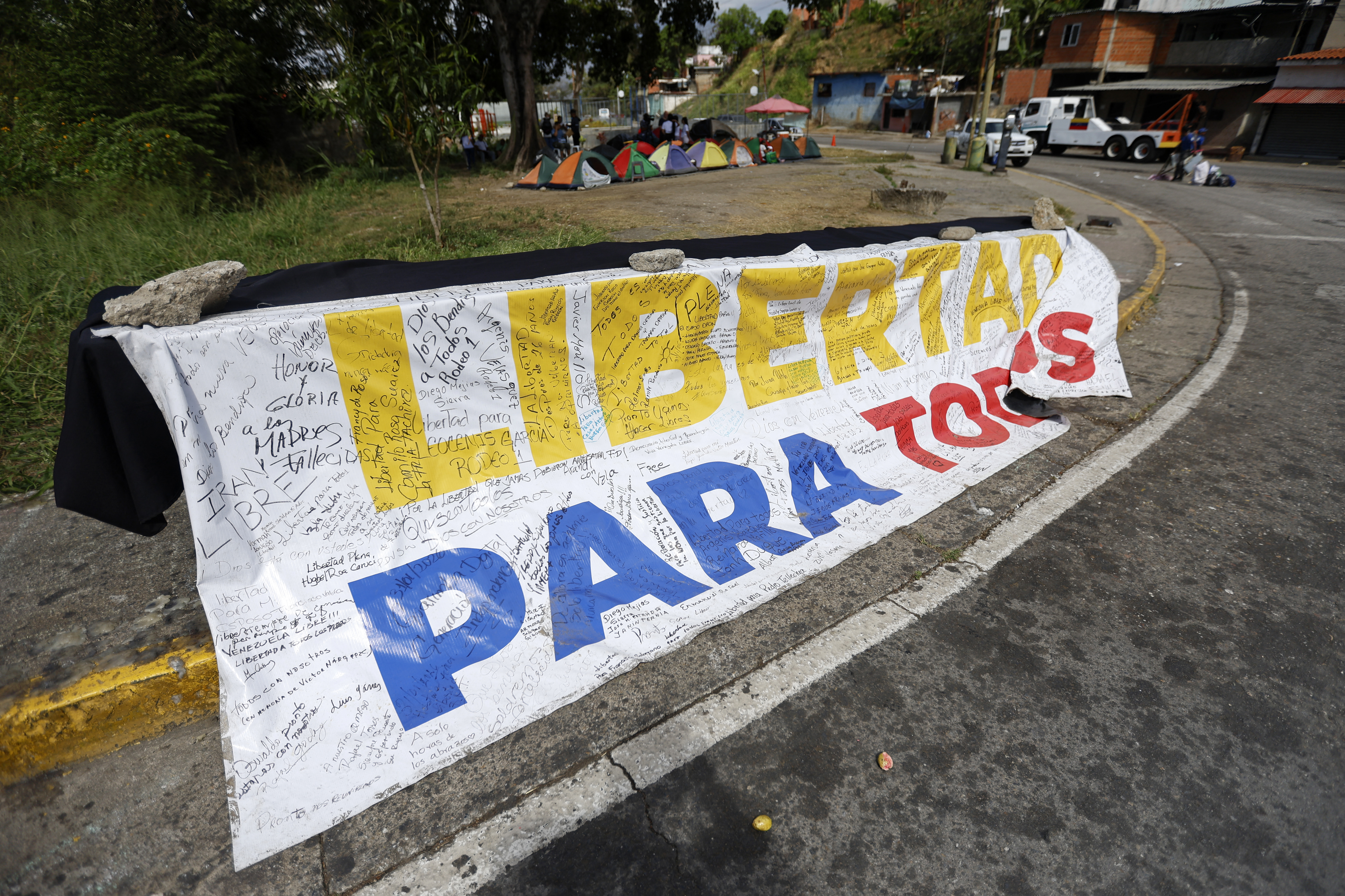 A banner reading "Freedom for all" is displayed in front of El Rodeo I prison in Guatire, Miranda state, Venezuela, on February 20, 2026. Venezuela's National Assembly on February 19 unanimously approved a long-awaited amnesty law that could free hundreds of political prisoners jailed for being government detractors. (Photo by Pedro MATTEY / AFP)
