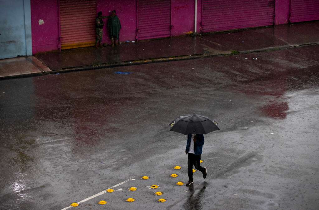 AMDEP7707. SANTO DOMINGO (REPÚBLICA DOMINICANA), 24/10/2025.- Un hombre camina usando una sombrilla este viernes, en Santo Domingo (República Dominicana). La tormenta tropical Melissa, que mantiene un comportamiento errático y casi estacionario, ha causado un muerto y fuertes inundaciones en la República Dominicana, donde más de un millón de personas están sin agua potable tras los daños sufridos en decenas de acueductos, mientras que más de mil han tenido que dejar sus casas por los efectos de las prolongadas lluvias. EFE/Orlando Barría