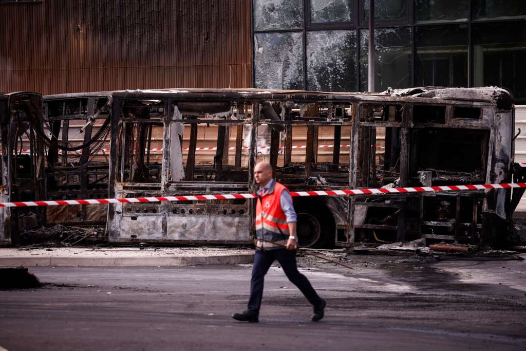 Aubervilliers (France), 30/06/2023.- An RATP employee walks past charred buses that were burned overnight at a public transport site in Aubervilliers, near Paris, France, 30 June 2023. Violence broke out all over France after police fatally shot Nael, a 17-year-old, during a traffic stop in Nanterre on 27 June. (Disturbios, Francia) EFE/EPA/YOAN VALAT