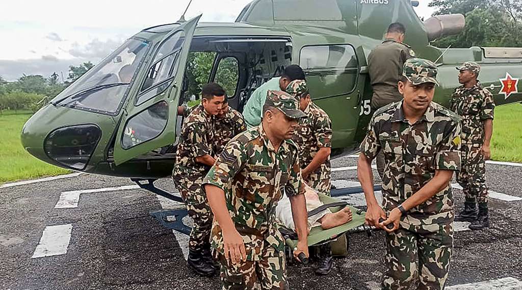 This handout photograph taken and released by Nepal's Army on October 5, 2025 shows Army personnel carrying a landslide victim evacuated by a helicoper following heavy rain-triggered landslides and floods in Nepal.