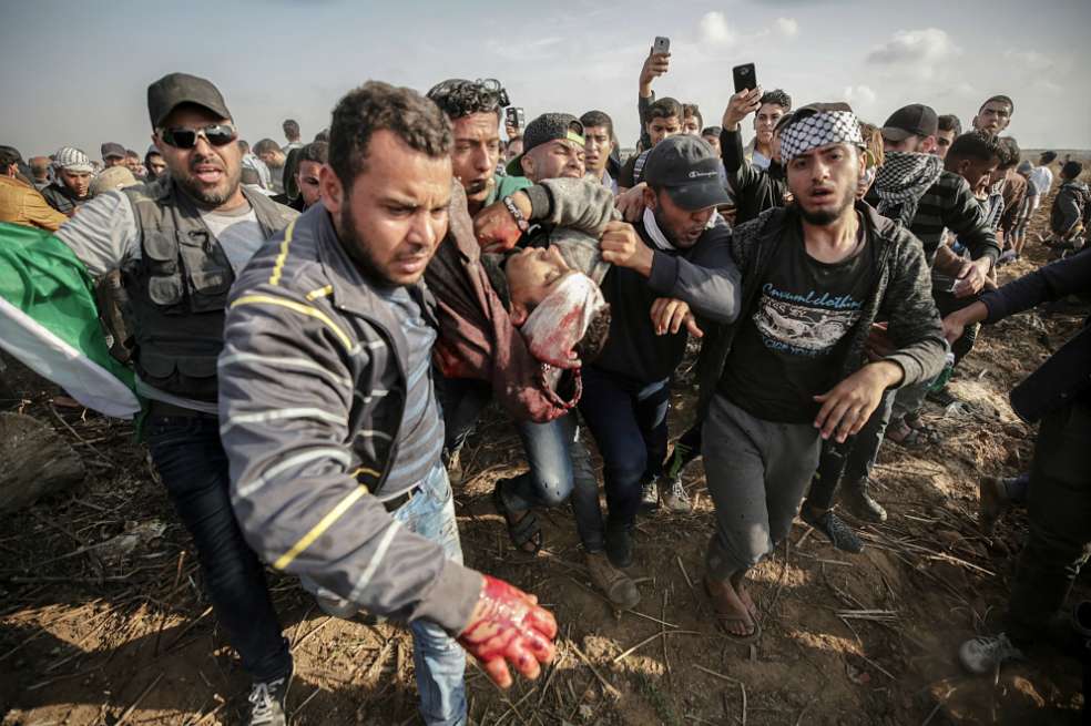 Varios palestinos intentan ayudar a un joven compañero herido de muerte durante los enfrentamientos con las tropas israelíes registrados en el este de la Franja de Gaza. / EFE