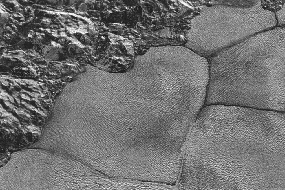 Cadena montañosa (arriba y a la izquierda) en la planicie helada Sputnik Planitia de Plutón, con las dunas en la mitad inferior derecha de la imagen, dentro de las estructuras poligonales. / EFE/NASA/jhuapl/swri