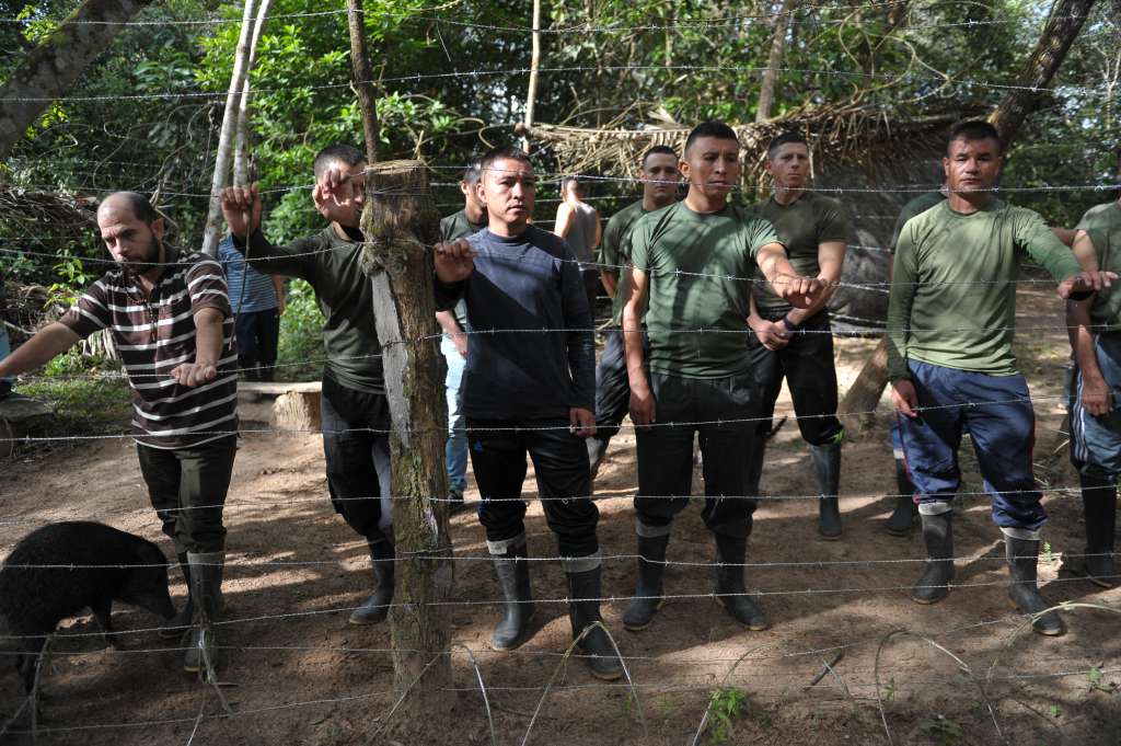 Hombres detrás de una red de púas, simulando el secuestro.