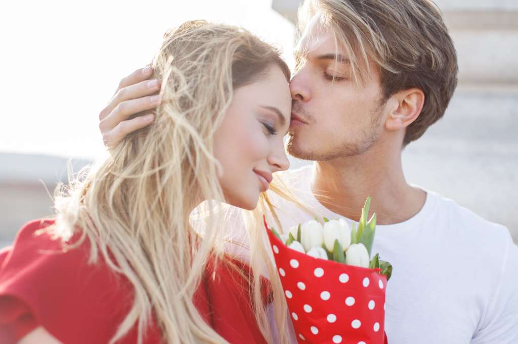 Young blonde man hug woman forehead outdoor