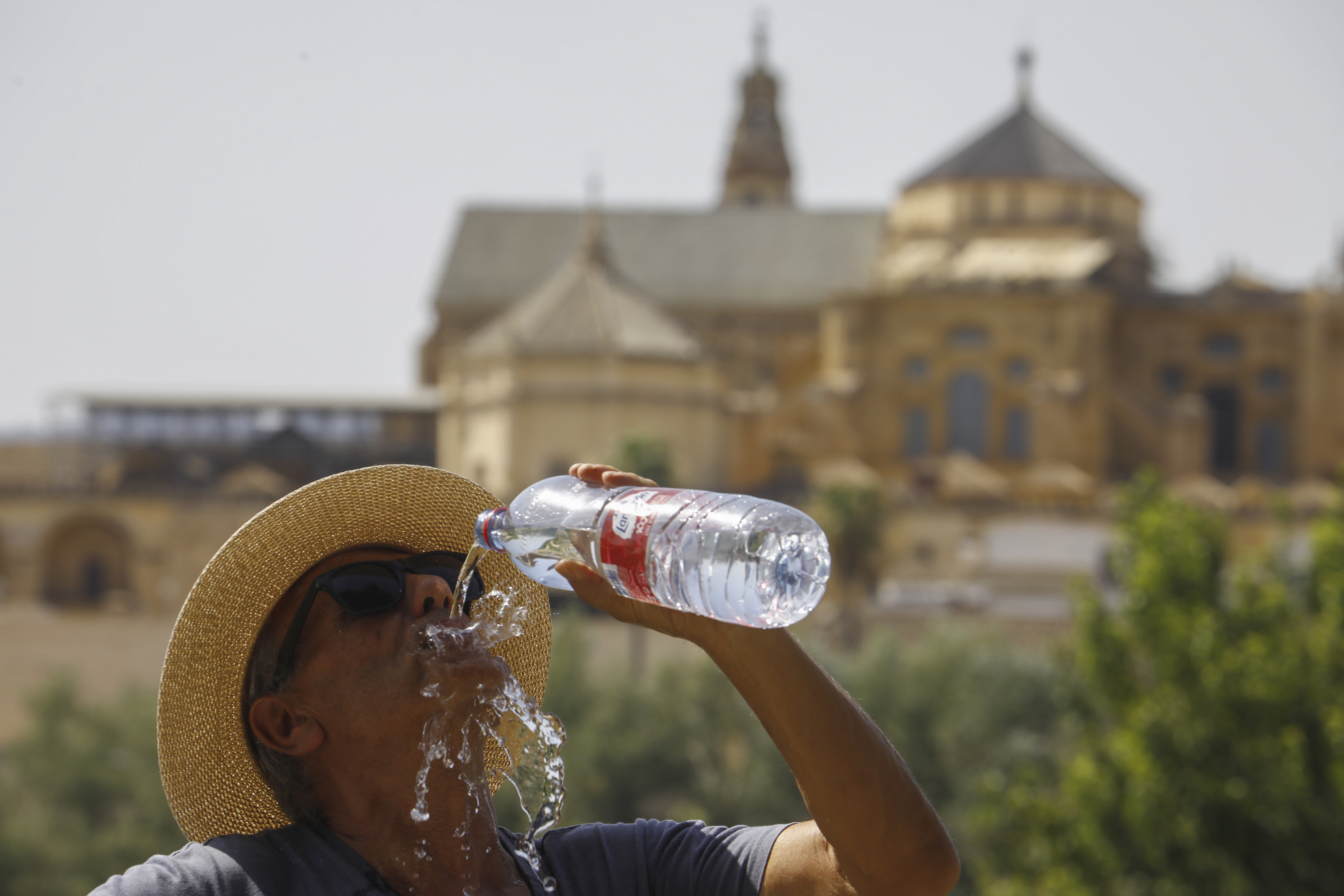 CÓRDOBA, 16/07/2022.- Un turista bebe agua ante la Mezquita-Catedral de Córdoba para combatir la ola de calor este sábado. La Agencia Estatal de Meteorología (Aemet) pone este sábado en alerta roja a cinco comunidades -Aragón, Cantabria, Extremadura, Navarra y La Rioja- en vista de las altas temperaturas, que podrán llegar a los 44 ºC durante la tarde, y sitúa a otras siete en aviso naranja. EFE/Salas