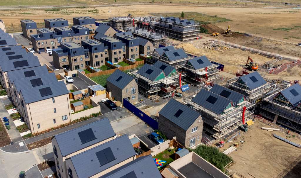 An aerial view shows newly built homes, and houses under construction, at a Keepmoat Homes construction site in Northstowe, eastern England on July 31, 2025.