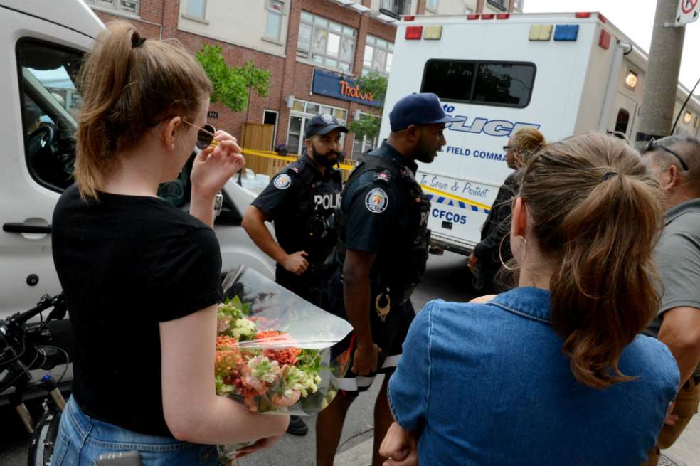 Familiares de las víctimas del tiroteo en el barrio griego de Toronto se acercaron a la escena para dejar arreglos florales. / AFP