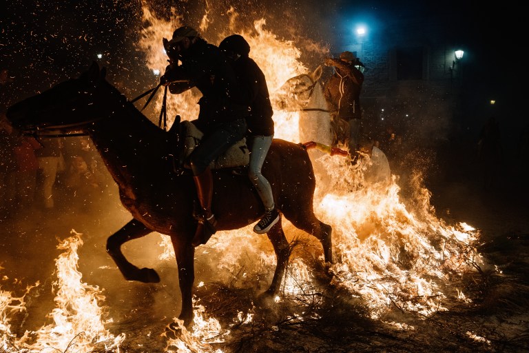 FOTOGALERÍA 7 DE 10.- SAN BARTOLOMÉ DE PINARES (ÁVILA), 16/01/2023.- Un jinete pasa con su caballo por encima de las llamas durante las tradicionales "luminarias" que se celebran hoy lunes en la localidad abulense de San Bartolomé de Pinares. EFE / Raúl Sanchidrián.