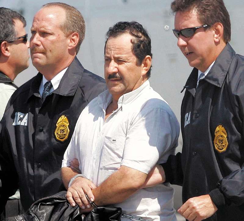 ** ADDS NAME HERNAN GIRALDO SERNA ** Colombian paramilitary Hernan Giraldo Serna, second right, is escorted by U.S. DEA Agents at his arrival in Opa-locka, Fla., Tuesday, May 13, 2008. Members of a Colombian paramilitary group arrived from Colombia to face U.S. drug trafficking and money laundering charges in federal court. (AP Photo/Alan Diaz)